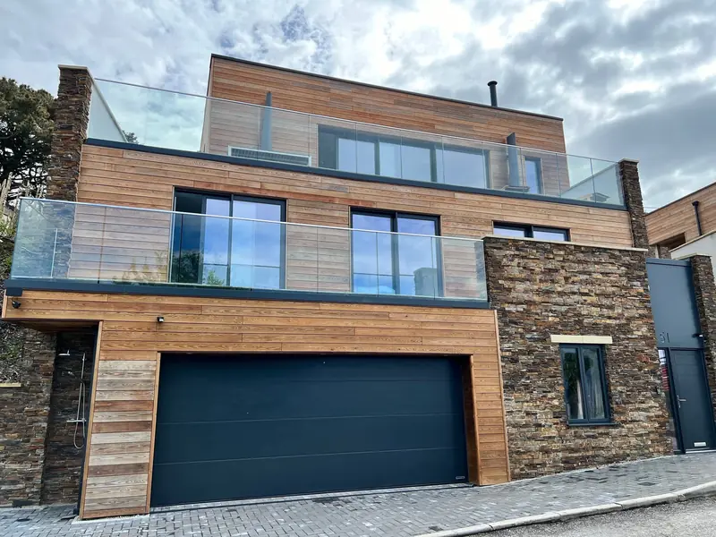 Front of Sunkeeper: a modern timber-clad and stone house with a garage